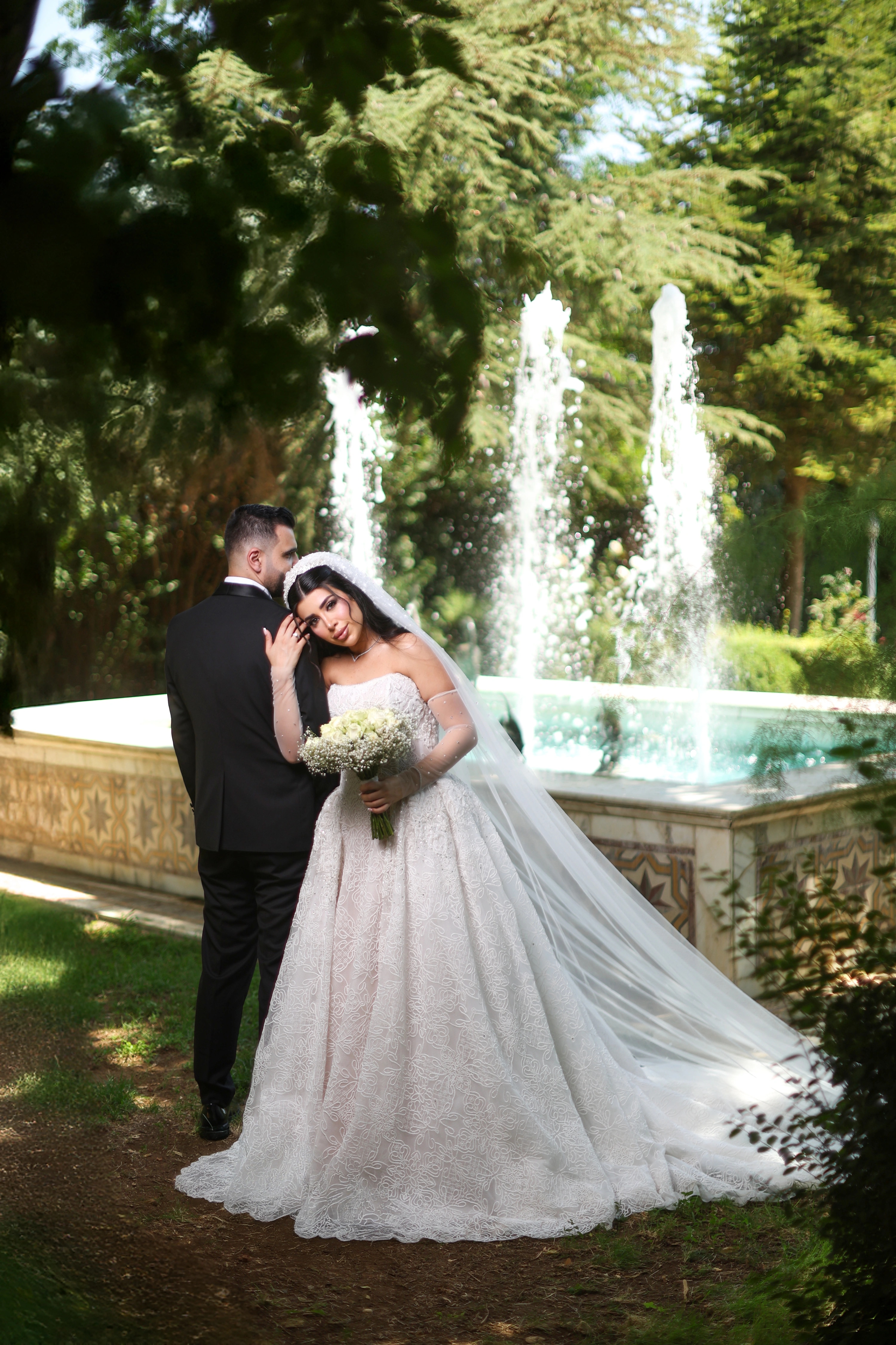 Bride and groom embracing beside a garden fountain