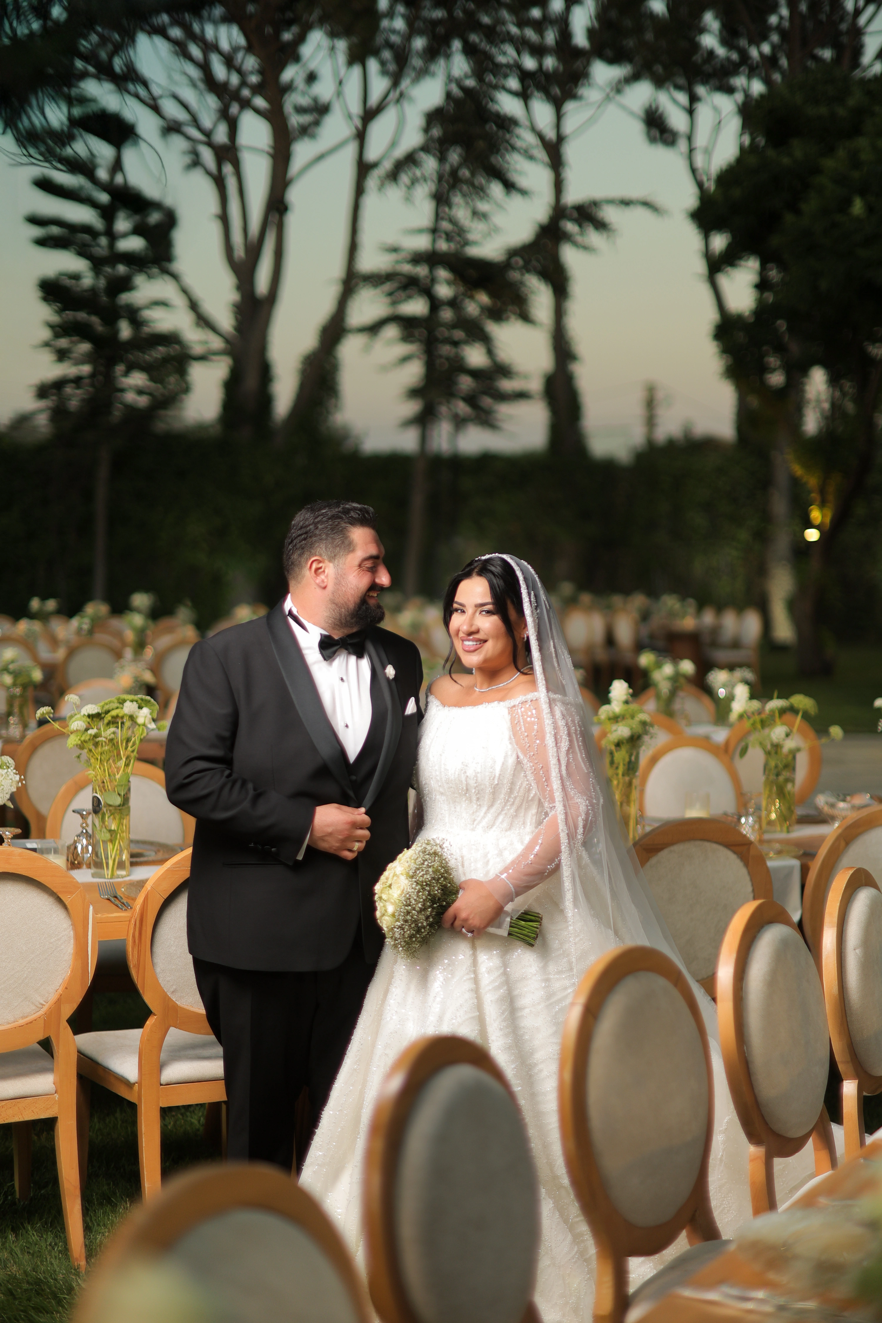 Bride and groom standing together among outdoor wedding reception tables