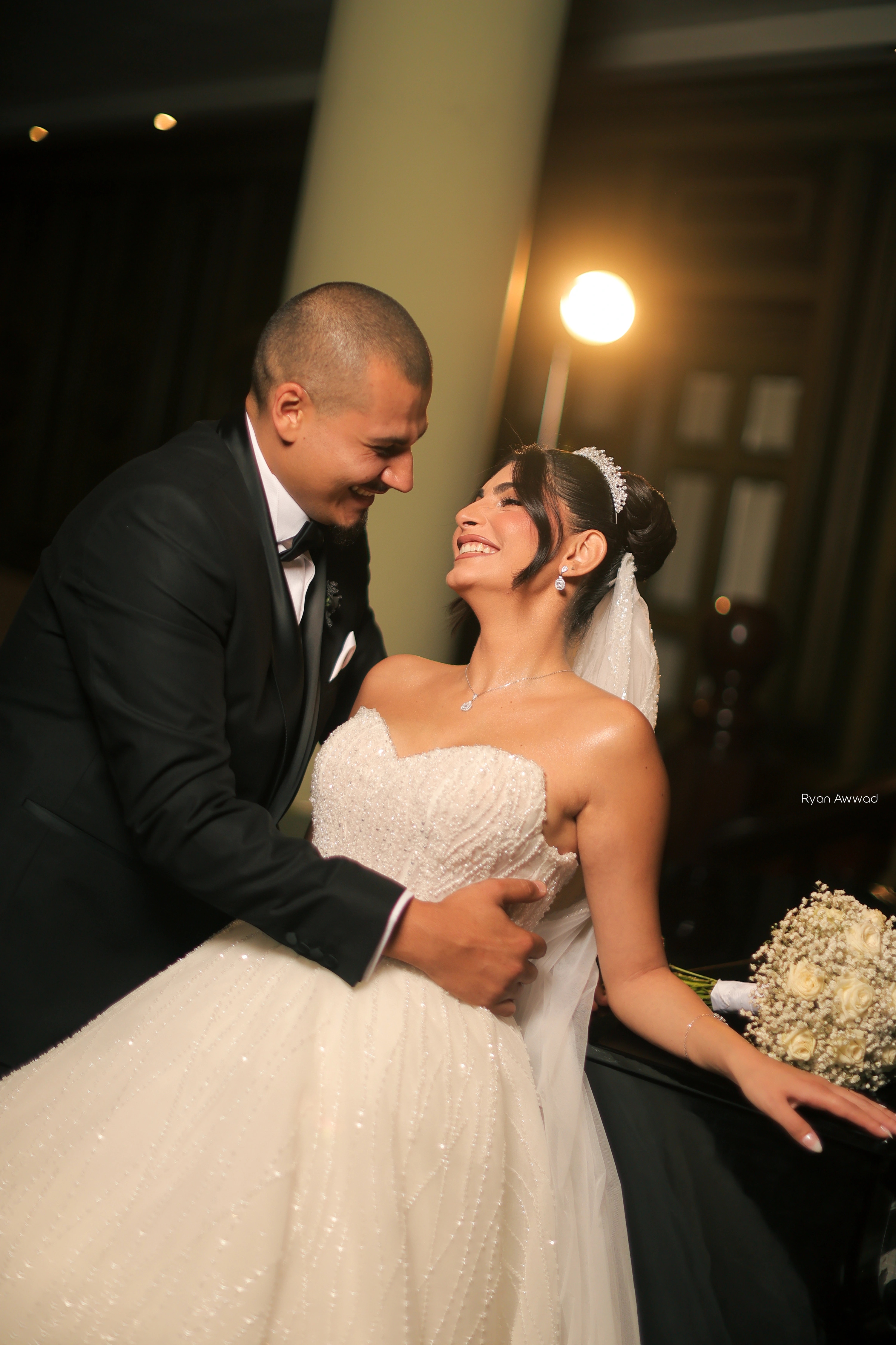 Bride and groom smiling together beside a floral arrangement